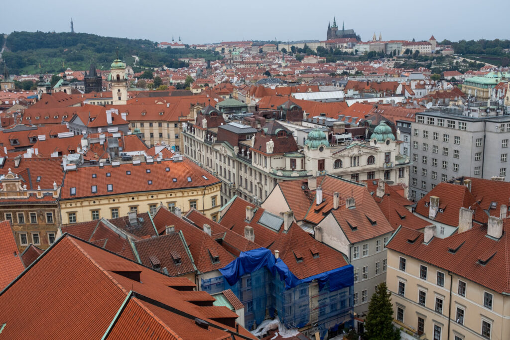 Pohled na Prahu z ptačí perspektivy. Činžovní domy a výhled na Pražský hrad. Odkazuje na výkup nemovitosí 